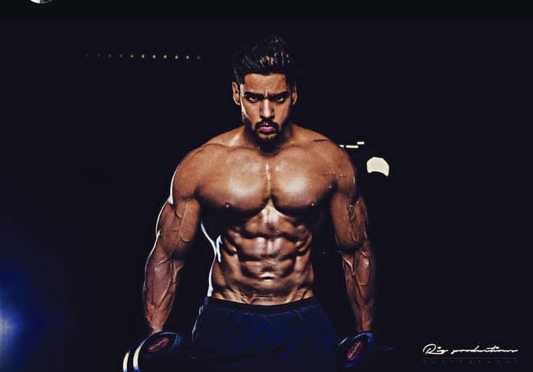 Abhinav Anand standing in front of a textured stone wall